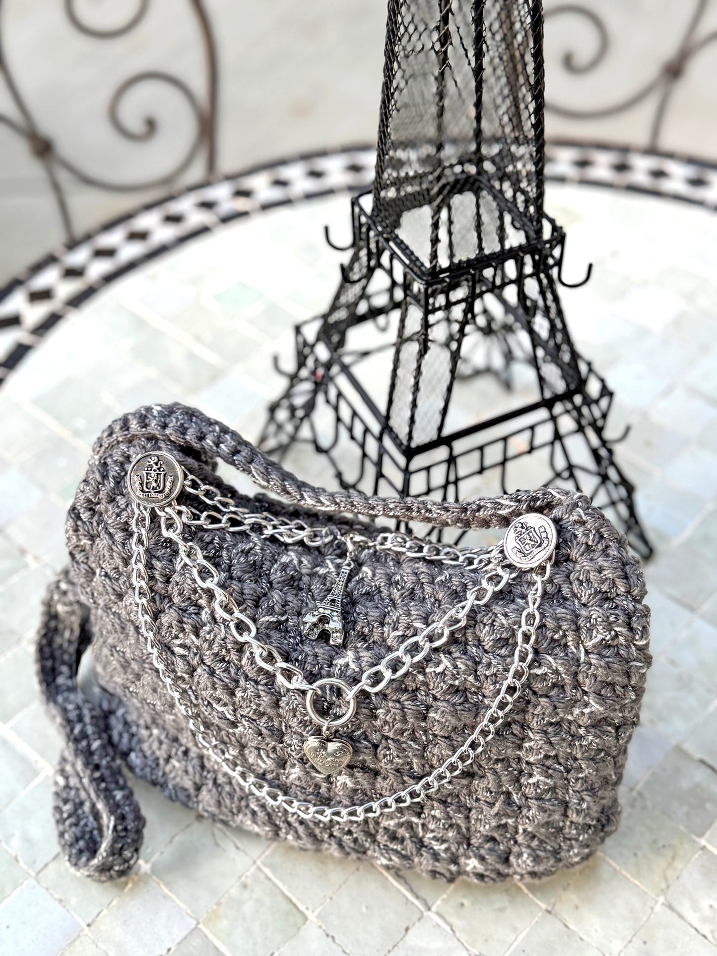 Parisian chic, the Amelie vintage crochet bag is adorned with slate gray lucite handles and chains & charms, reflecting the beauty and love of Paris. The expert craftsmanship and high quality, sustainable acrylic yarn of this artisanal piece does not require a lining. Double functionality with added shoulder strap can be neatly tucked inside when not in use. Dimensions: Width: 10", Height: 11"(with handles), Strap: 17.5" Spot Treat or Dry Clean only Consciously made in California