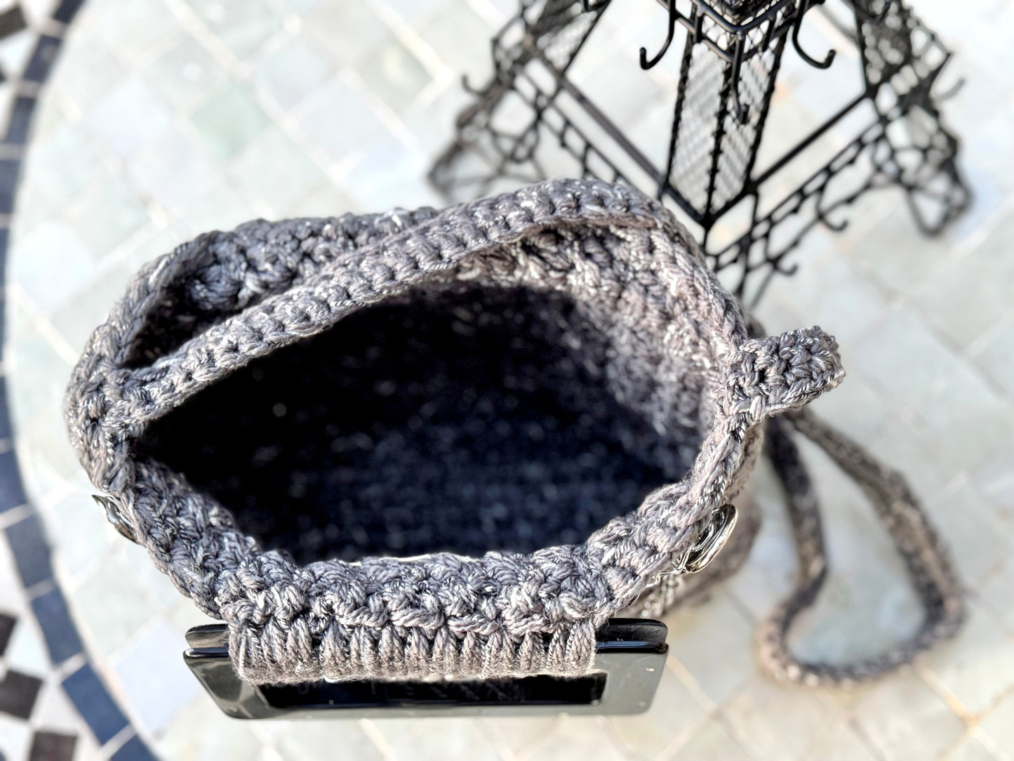 Parisian chic, the Amelie vintage crochet bag is adorned with slate gray lucite handles and chains & charms, reflecting the beauty and love of Paris. The expert craftsmanship and high quality, sustainable acrylic yarn of this artisanal piece does not require a lining. Double functionality with added shoulder strap can be neatly tucked inside when not in use. Dimensions: Width: 10", Height: 11"(with handles), Strap: 17.5" Spot Treat or Dry Clean only Consciously made in California