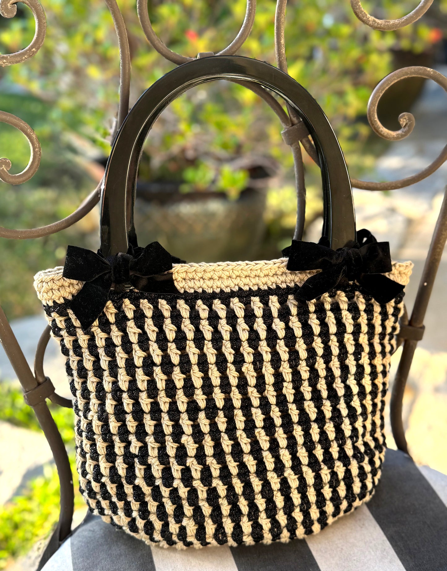 Feeling so French with daytime chic, Basque crochet tote. Up-cycled cotton blend and nylon yarns in a linear stripe pattern with velvet bows and large black Lucite handles to wear over your shoulder. Two interior pockets are ideal to store your phone and sunglasses. Dimensions: Height: 10" Length: 12" Width: 7" Handles: 6.5" x 6" high (inside of handle measurement) Spot treat with mild soap or dry clean Consciously made in California
