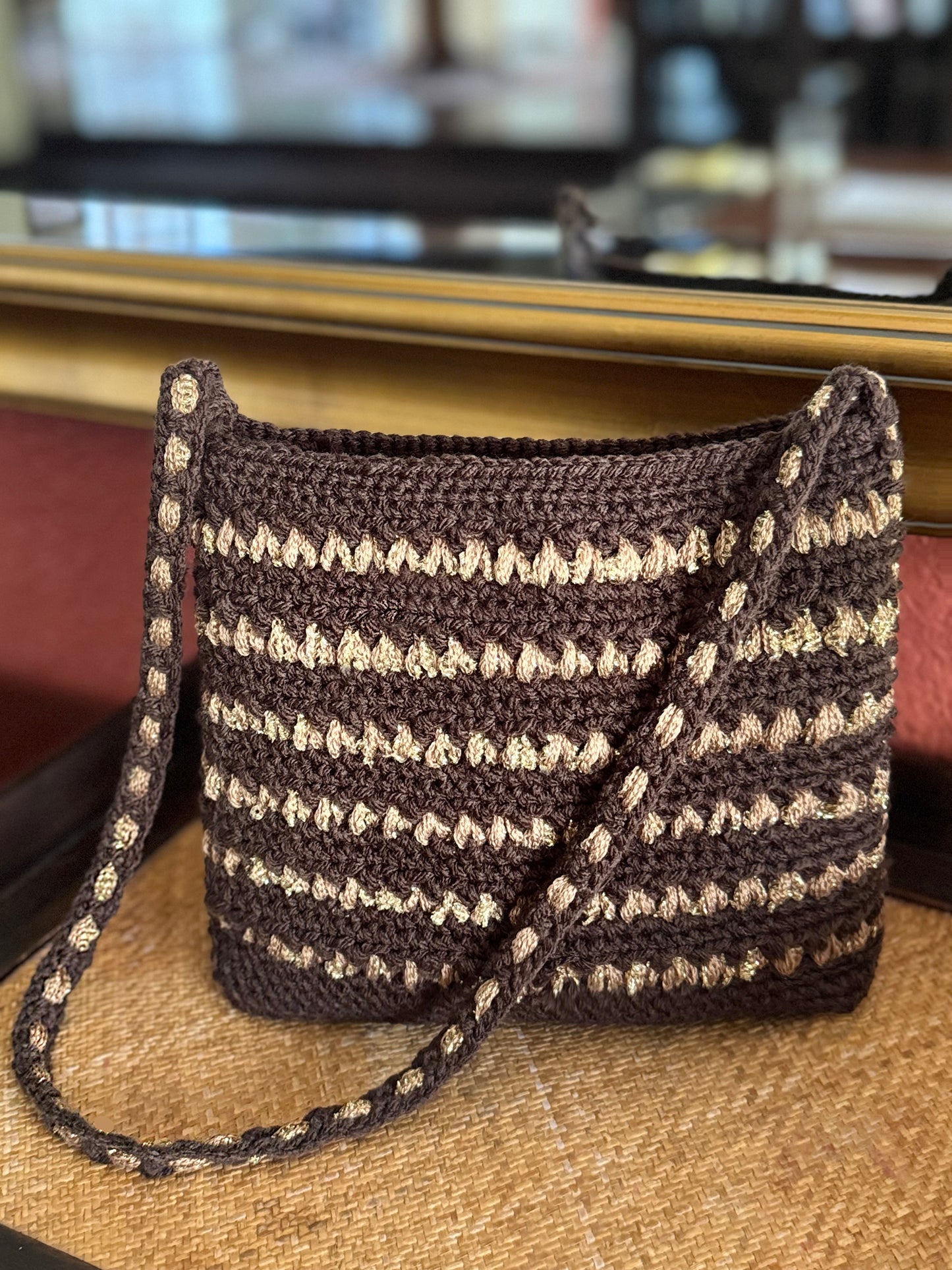 Fall's sparkle of gold and bronze are this season's popular accents on our metallic stripe, crochet bags handcrafted with up-cycled acrylic & metallic yarn in a beautiful shoulder strap style with a metallic stripe pattern in fall colors. *Burnt orange/bronze bag has a vintage rhinestone pendant closure. Dimensions: Gold/Coffee - 10" long, 9" high (with strap 24"), 4" wide Burnt Orange/Bronze - 7.5" long, 6" high (with strap 16"), 2.5" wide 100% Acrylic yarn - Hand wash, cold, flat surface dry Available for