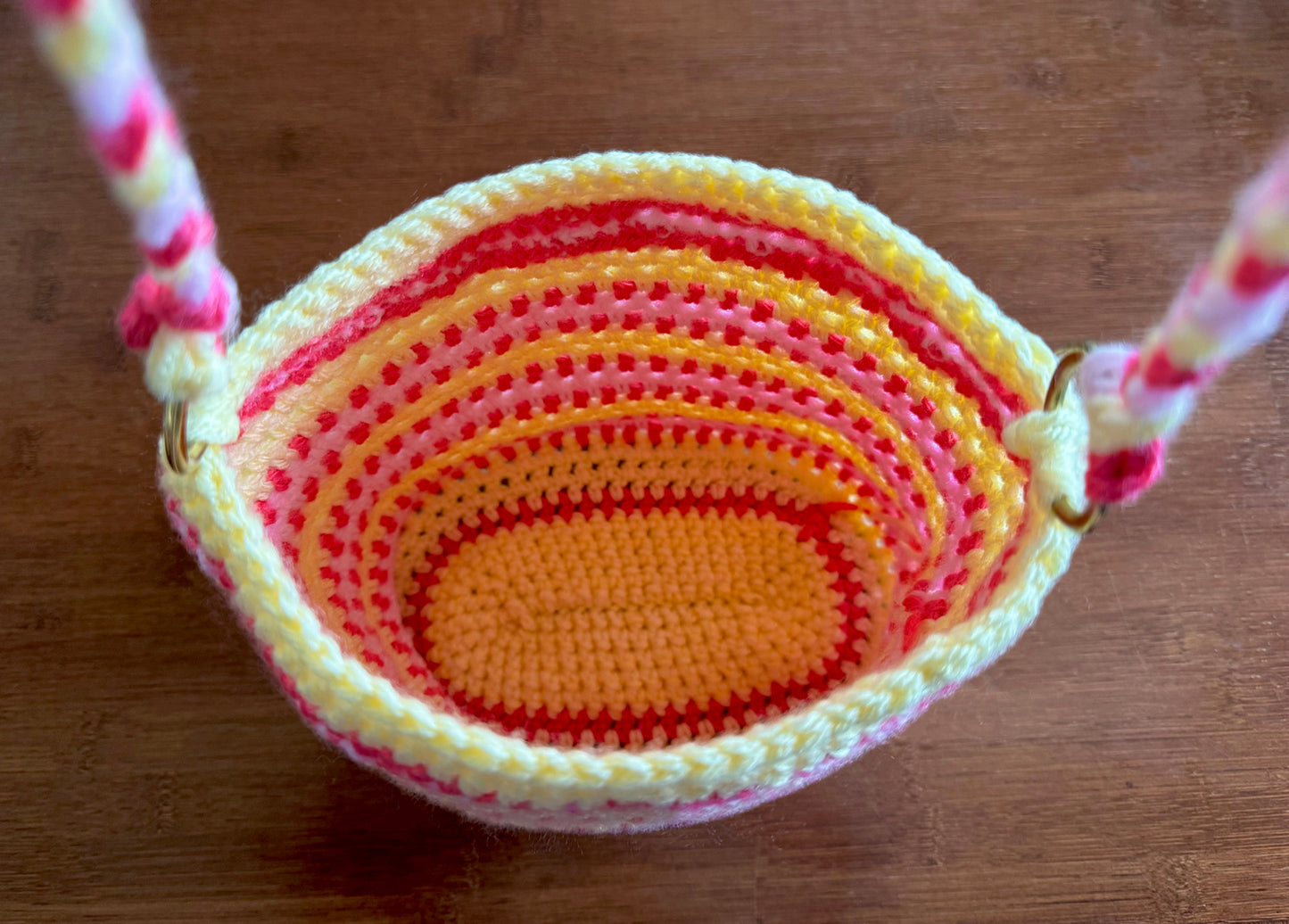 Girls and Tweens love the Charlotte Bucket Bag. Hand crocheted with up-cycled acrylic yarn in a beautiful stripe pattern of yellow, red and pink, including two brass rings to connect the braided strap. The perfect bag to carry little crochet plushy pets. Dimensions: 9" long, 8" high (14" strap from top of shoulder), 5" wide Spot treat, dry clean Consciously made in California