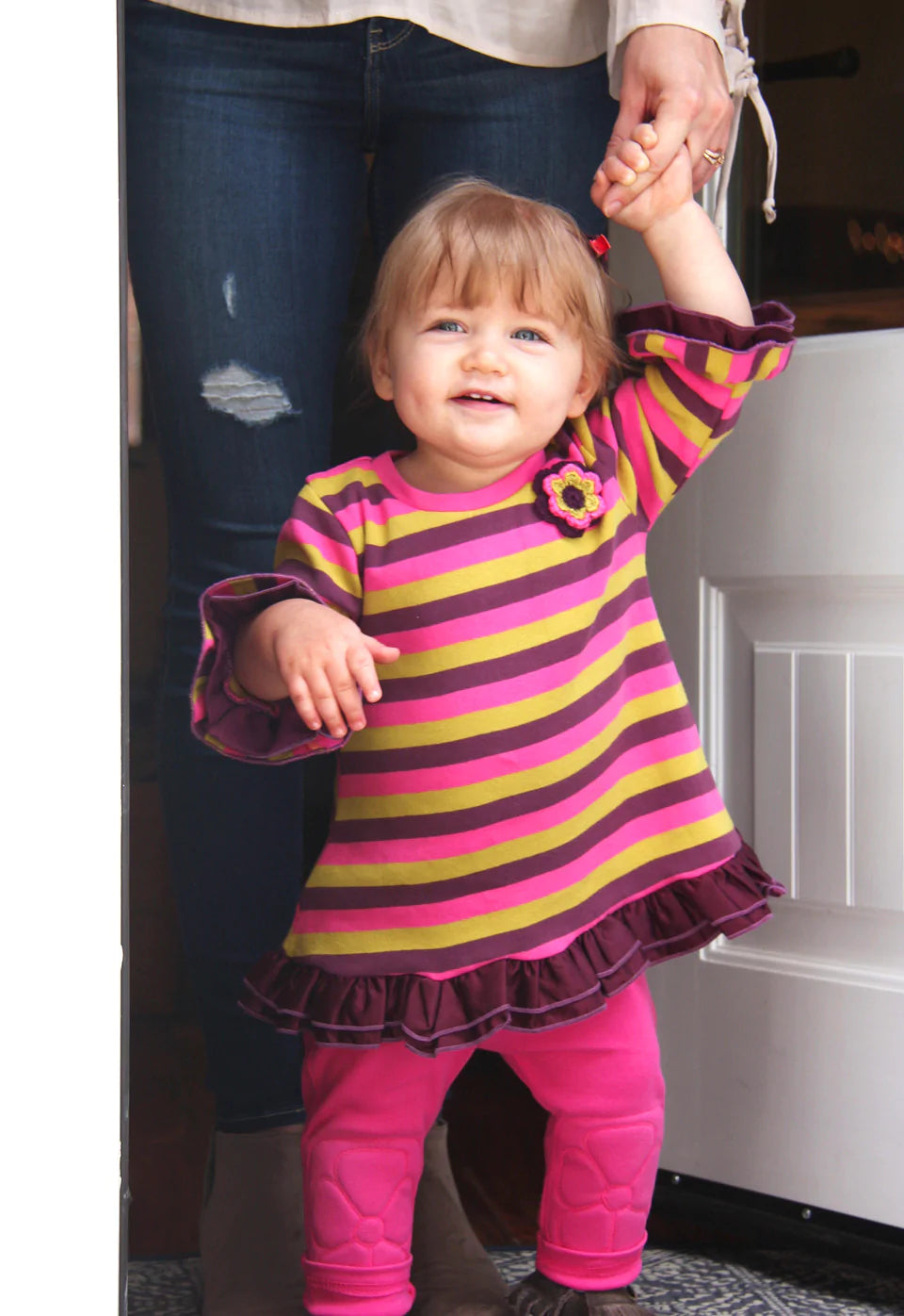 70's model icon,Twiggy, inspired this A-line striped knit dress with ruffled 3/4 sleeves and hem. Made from the softest, combed cotton rib knit and hand detailed with satin ruffles and crochet flower embellishment. Toddler sizes have turtle neck style, and infant sizes have a crew neck stretch binding. Machine washable, Cold, Delicate Cycle, Line Dry Consciously made in the Jammin' USA