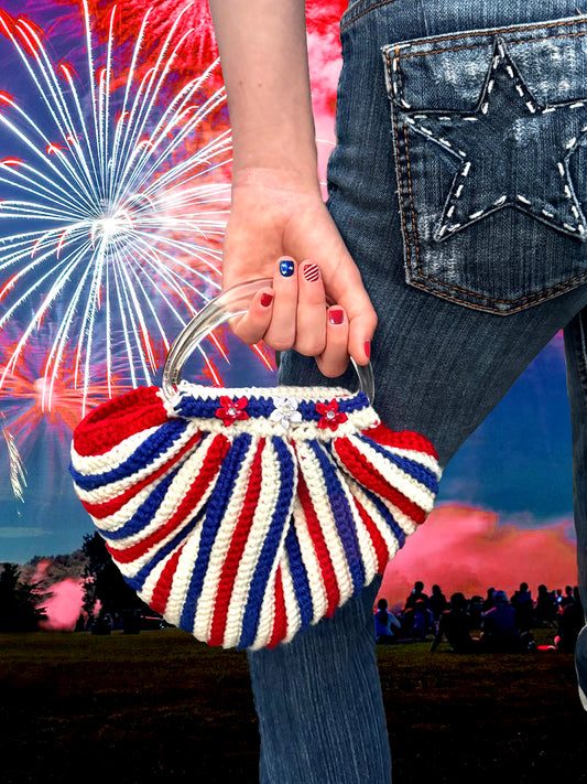 Get into the spirit of the red, white and blue with this festive bag, bedazzled with rhinestone star flowers. Up-cycled acrylic yarn in red, white & blue with twin clear Lucite handles. Hand crocheted by Oda G. exclusively for MarVia Square. Dimensions: Height:10.5"(including handles) Length:10" Width: 3" Spot treat or hand wash cold with mild soap Consciously made in California