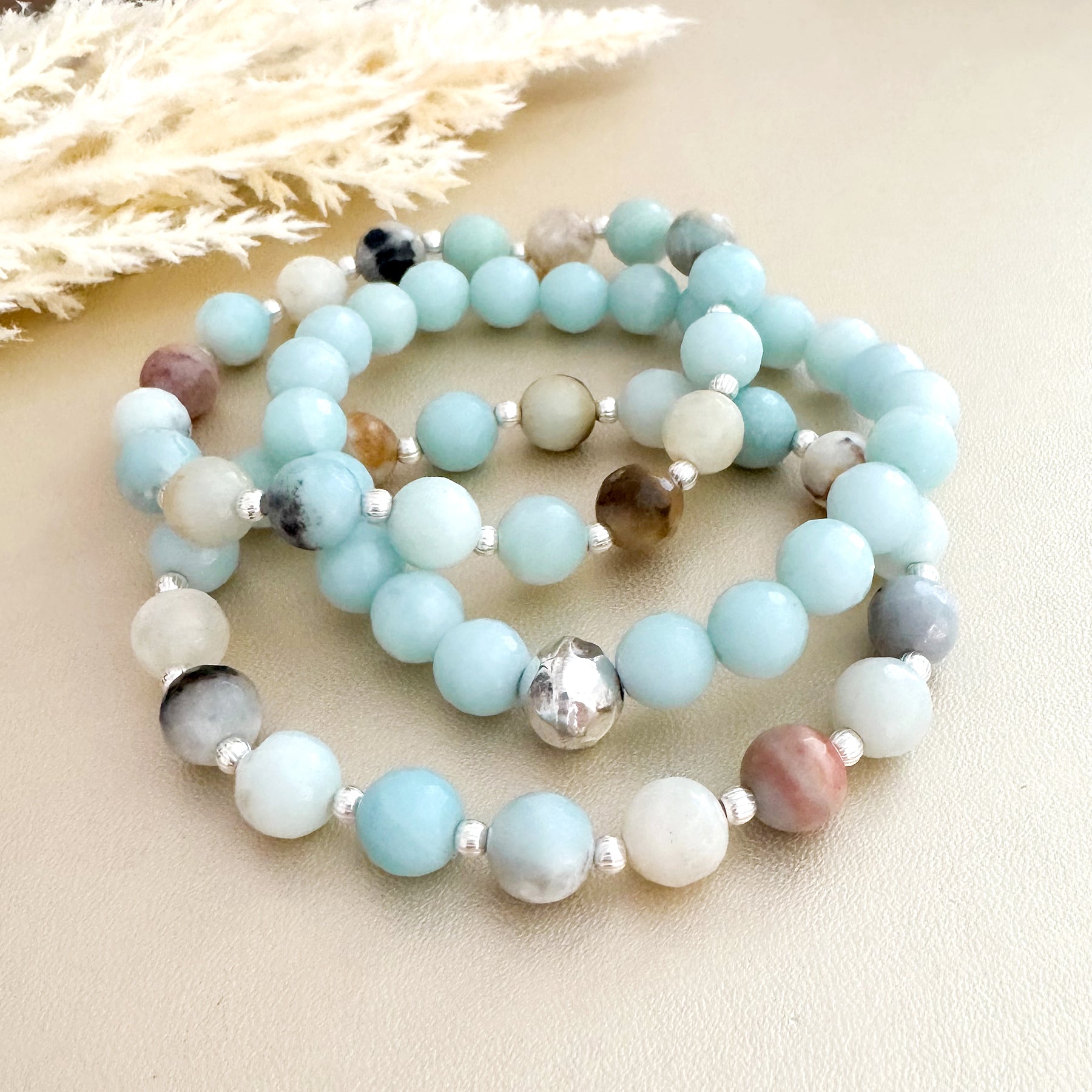 Feel good and look beautiful in 'Just Good JuJu' gemstone trio bracelets. The trio of Amazonite with sterling silver bead accents, has powerful healing properties, encouraging emotional balance, harmony, good luck and fortune. The trio of Rose Quartz and faceted petrified wood with 14k gold filled bead accents, has healing properties of calm, compassion and love. Each bracelet has stretch cord to fit most wrist sizes. Dimensions: Amazonite - (2) 8mm stones, silver bead accents, (1) 8mm stones with one 8mm s