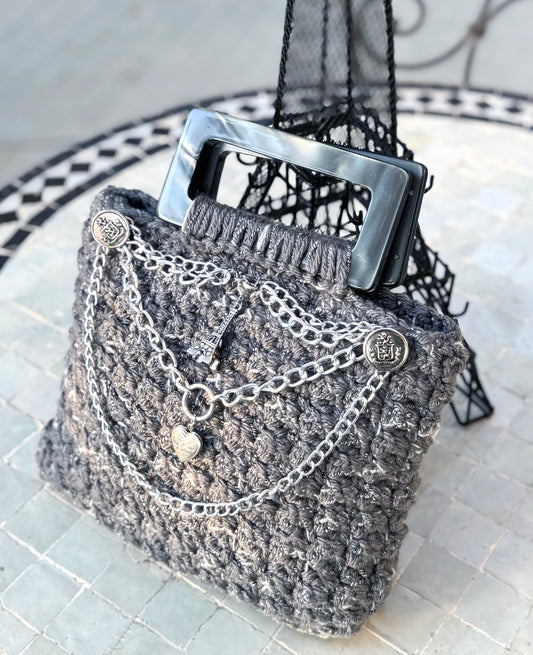 Parisian chic, the Amelie vintage crochet bag is adorned with slate gray lucite handles and chains & charms, reflecting the beauty and love of Paris. The expert craftsmanship and high quality, sustainable acrylic yarn of this artisanal piece does not require a lining. Double functionality with added shoulder strap can be neatly tucked inside when not in use. Dimensions: Width: 10", Height: 11"(with handles), Strap: 17.5" Spot Treat or Dry Clean only Consciously made in California