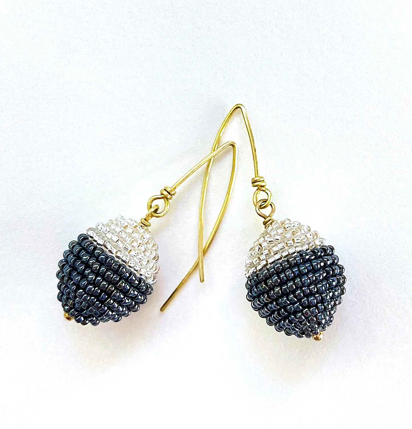 Artist, Iva Hladis, has created an exquisite collection of elegant beaded earrings that will stand out in any event. Black & White - B&W wool ball embellished with glass micro beads, brass earwire & headpin. Length: 1 5/8" Ball: 3/4"