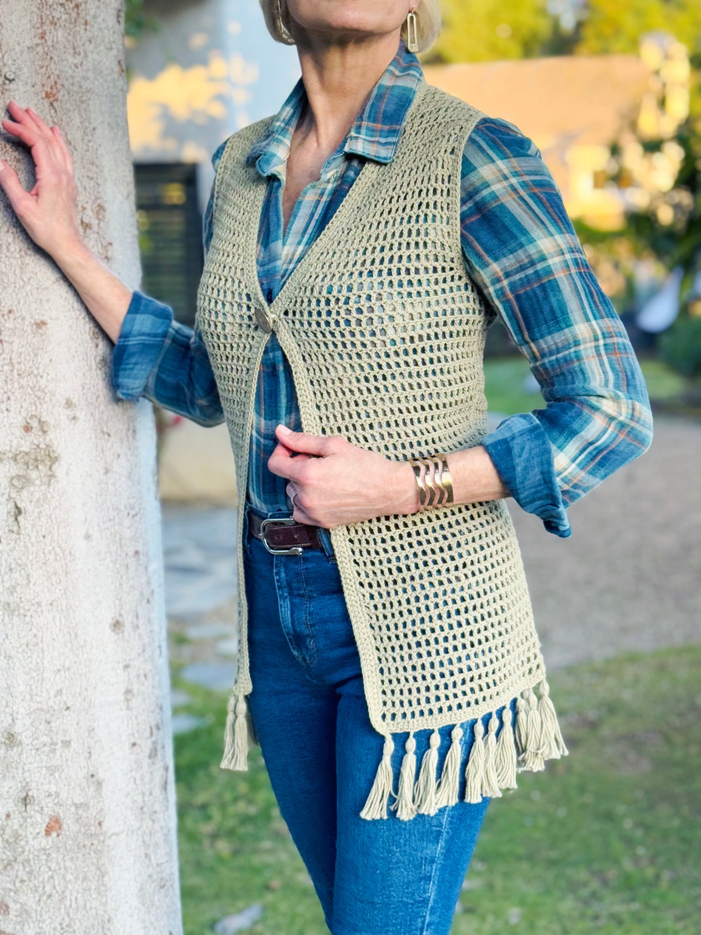 Hand crocheted with up-cycled, cotton blend yarn, this long style crochet vest in a beautiful sage color, fits small and medium sizes. Fun fringe trim on bottom hem and vintage silver button, snap closure at the bust. Size: Small / Medium Length: (from top of shoulder) Front - 32", Back - 33" Hand wash cold, Line dry or Dry clean Consciously made in the USA