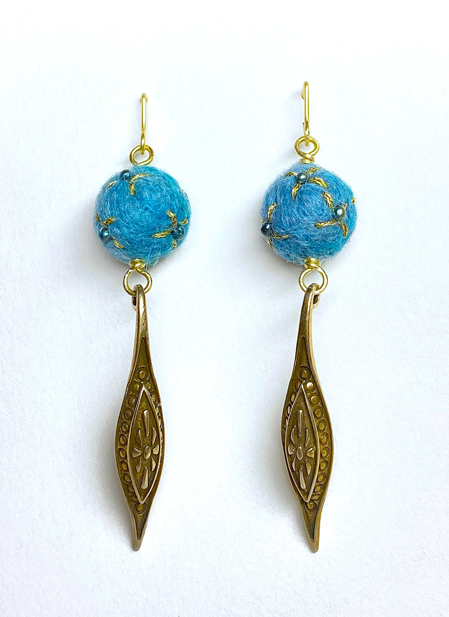 Pair of earrings with blue wool small balls, embellished with fresh water cultured pearls, gold leaf designs, and a brass drop pendant. 