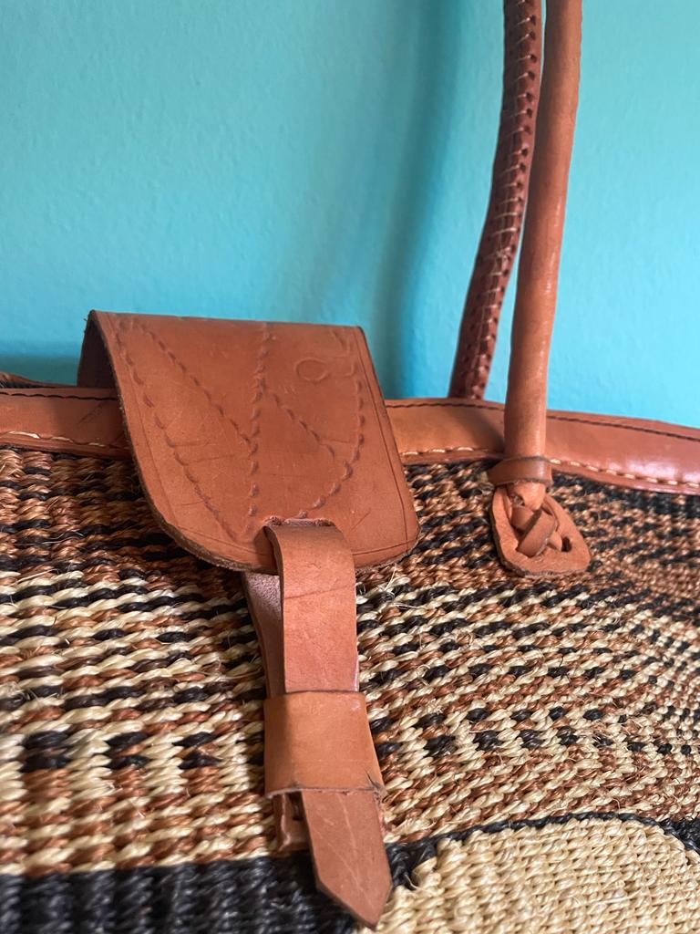 These hand woven sisal bags from Kenya are made by generations of women artisans, who have learned the art of weaving from their mothers and grandmothers. Sustainably sourced sisal fibre, natural dyes, and highest quality vegetable tanned leather, create a beautiful blend of Kenyan culture and artistry. Each bag has it's authentic, one-of-a-kind style, and is the perfect accessory for the summer. Dimensions: 17w x 14h Made in Kenya