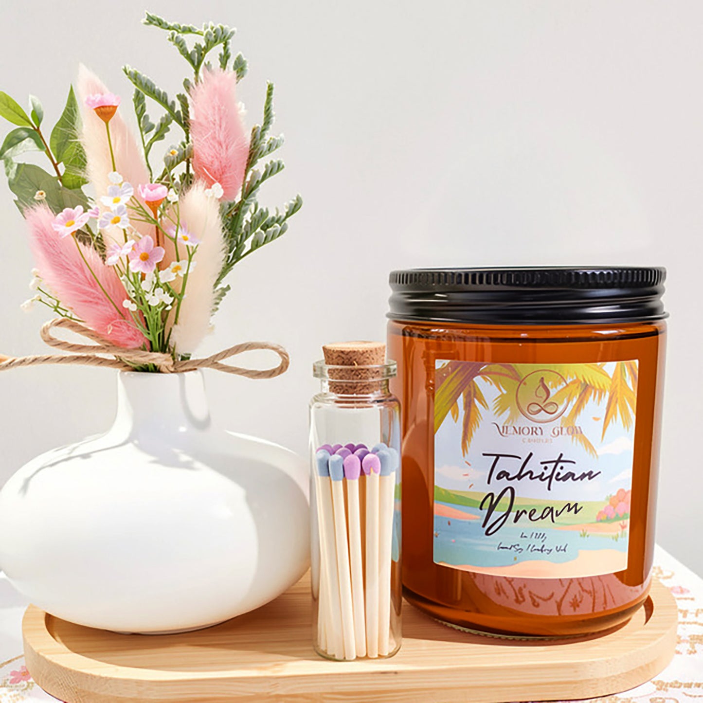 Tahitian Dream candle is a luxurious, island escape blend of Lily, Jasmine, Sugar Amber, and Musk with Tahitian Vanilla. Hand poured with long lasting soy & coconut wax and natural wood wick in an 8 oz. amber jar or 2oz. travel size tin. As a set, plumes of bohemian pampas grass are combined with silk flowers in an ivory ceramic vase, along with a cork topped glass vile of wood matches.
