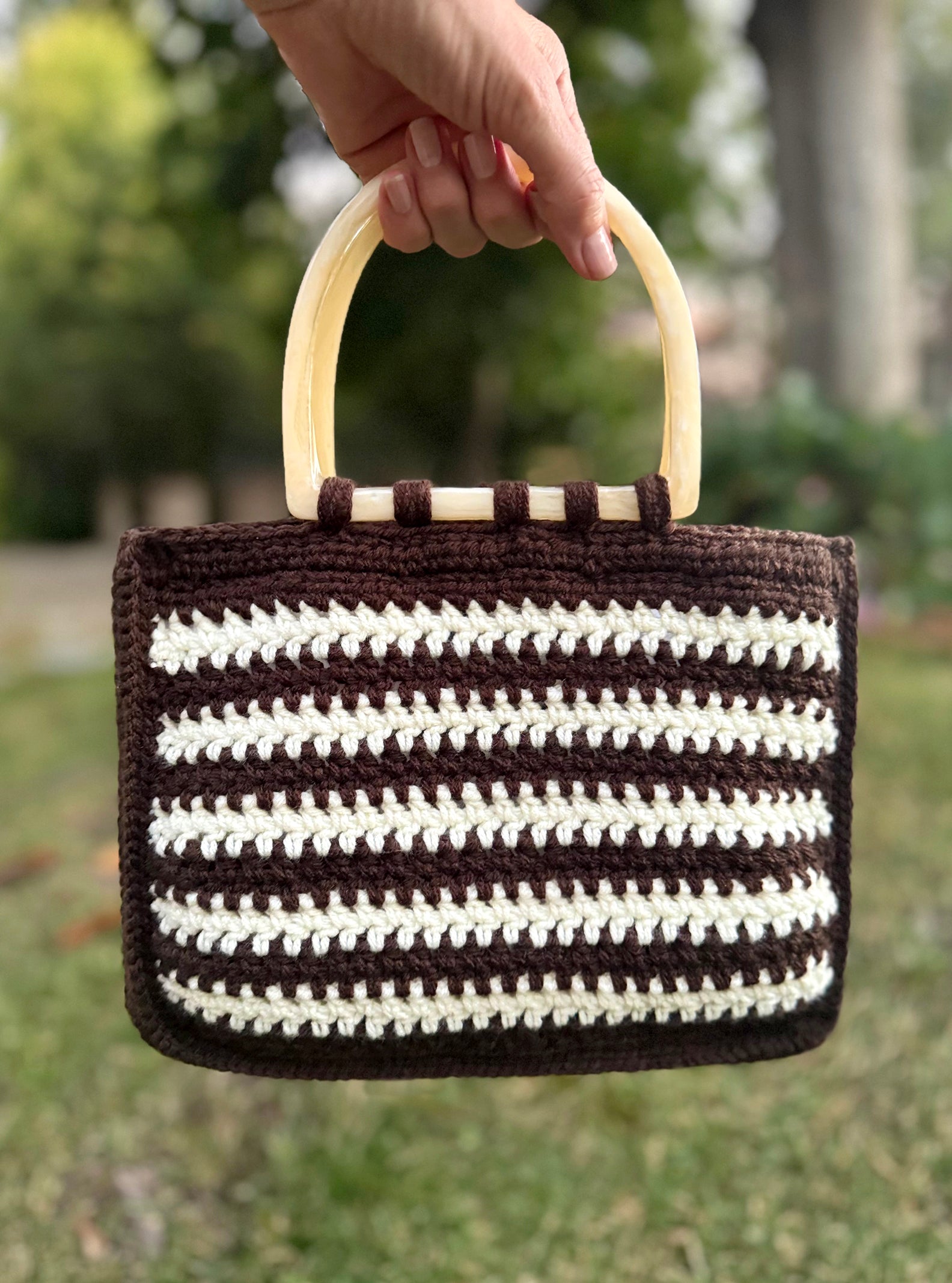 Italian vintage style Sienna Bag takes us back to the 60's, with cream color lucite handles, and acrylic yarn, hand crocheted in a striped pattern. Dimensions: Bag - 11" wide, 9" high, Handles - 5.5" x 5" Hand wash with mild soap, cold water, or Dry Clean Made in the USA